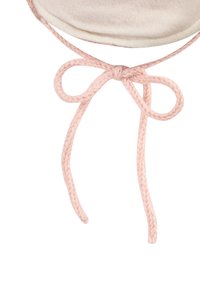 Close-up of a soft beige bonnet with a pink braided string tied in a bow on a white background.