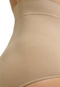 Beige hoge taille corrigerende slip met geribbeld textuur, brede tailleband en een gladde afwerking. Ontworpen voor naadloos draag comfort onder kleding.