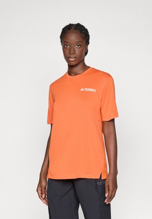 T-shirt orange à manches courtes en tissu lisse, avec un col rond et un petit logo TERREX blanc sur la poitrine gauche.