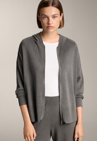 Graue Zip-Cardigan aus weichem, geripptem Stoff mit Kapuze. Mit lockerer Passform, überschnittenen Schultern und glatter Textur.