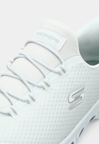 Ελαφρύ αθλητικό παπούτσι από δίχτυ σε λευκό και ανοιχτό γκρι. Διαθέτει ελαστικά κορδόνια, υφασμάτινο ανώτερο μέρος με υφή και λογότυπο στο πλάι. Λαστιχένια σόλα.