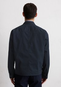 Dark navy jacket made of smooth fabric, featuring a classic collar, buttoned cuffs, and a straight cut, shown from the back.