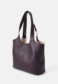 Large dark purple leather tote bag with textured surface, two sturdy handles, and a gold hardware accent on the side. Interior shows a light color.