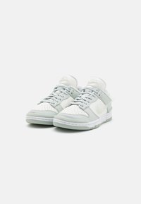 Nike Dunk Low sneakers med en ovandel i vit läder med ljusgrå detaljer, perforerat tåparti, snörning och en vit gummisula.