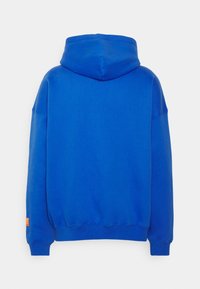 Sweat à capuche en bleu vif. Confectionné dans un matériau doux avec une coupe ample. Comprend une poche kangourou et des poignets côtelés avec un accent d'étiquette orange.