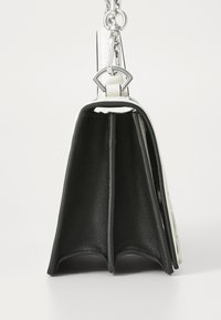 Borsa strutturata in bianco e nero con finitura in pelle liscia, tracolla a catena e un design unico a due scomparti. Presenta dettagli metallici.