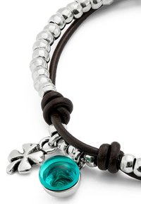 Pulsera de cuero con cuentas de plata, un encanto de vidrio turquesa y un acento de cruz plata. Presenta cuero marrón oscuro y detalles de plata pulida.