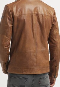 Brun læderjakke med en glat tekstur, tætsiddende design og kontrastsyninger. Har lynlåse ved ærmekanterne og en rygstykke detalje.