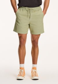 Lys grønne shorts med elastisk talje og justerbar snor. Har sidelommer og lige ben, lavet af blødt stof.