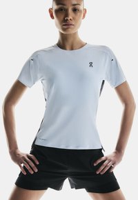 T-shirt de sport à manches courtes en bleu clair avec une surface texturée, des accents latéraux noirs et un logo. Assorti à un short de sport noir.