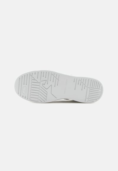 Semelle d'une chaussure blanche avec différents motifs de bande de roulement texturés pour l'adhérence, présentée sur un fond clair uni.