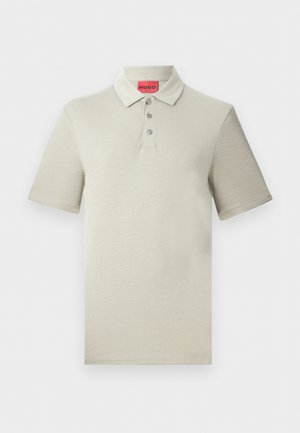 Polo beige à manches courtes avec trois boutons et un col rabattable, doté d'une étiquette rouge HUGO à l'intérieur du col.