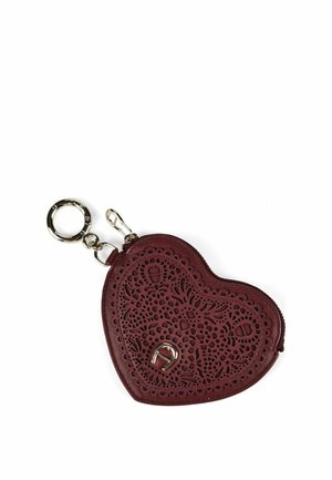 Heart-shaped maroon leather keychain pouch with intricate laser-cut floral patterns and a small silver horseshoe emblem.