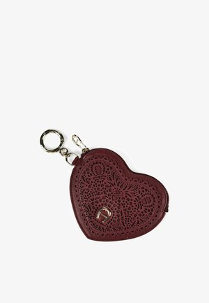 Pochette porte-clés en cuir bordeaux en forme de cœur avec des motifs floraux délicats découpés au laser et un petit emblème fer à cheval en argent.