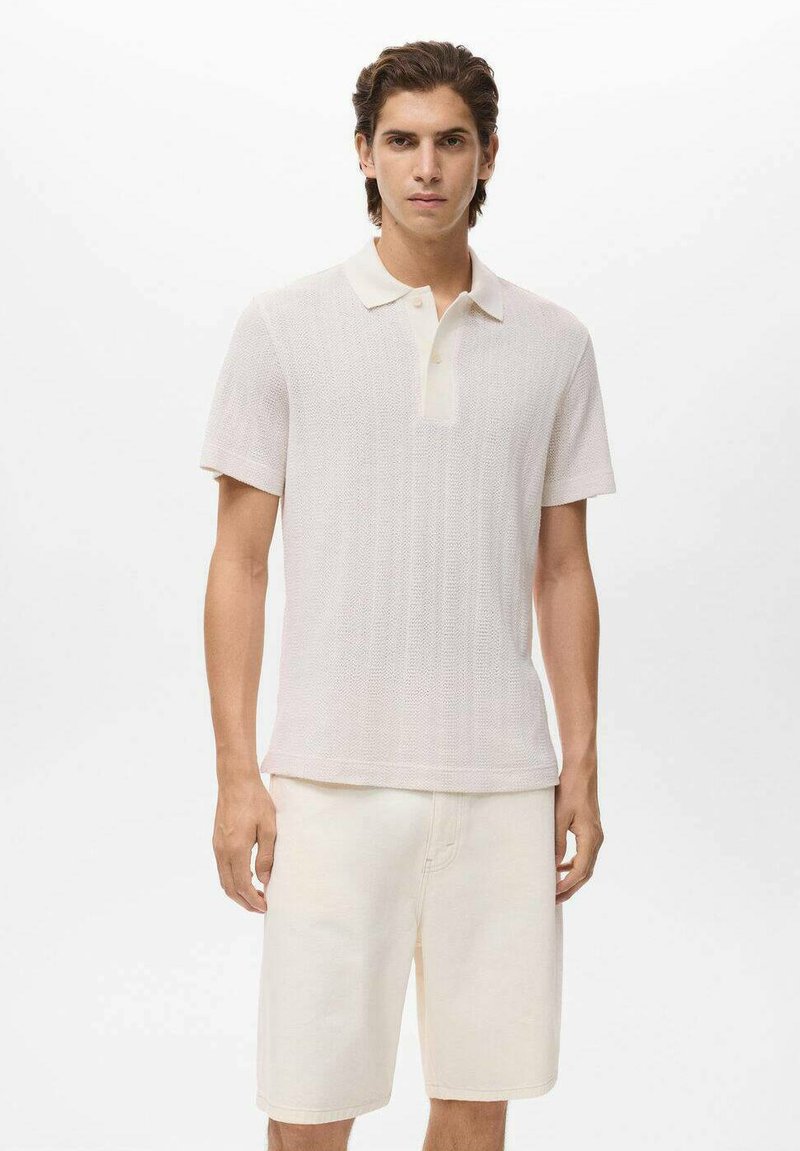 Kortærmet polo t-shirt i lys beige med et struktureret mønster og en kontrastfarvet off-white krave, parret med lyse beige shorts.