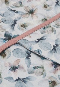 Tecido floral em suaves cores pastel, apresentando um design em aquarela de folhas e flores. Com uma borda fina em rosa.