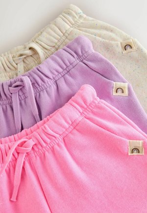 Stos trzech złożonych spodni dresowych w beżowym melanżu, lawendowym i jaskraworóżowym z elastycznymi pasami i sznurkami na białym tle.