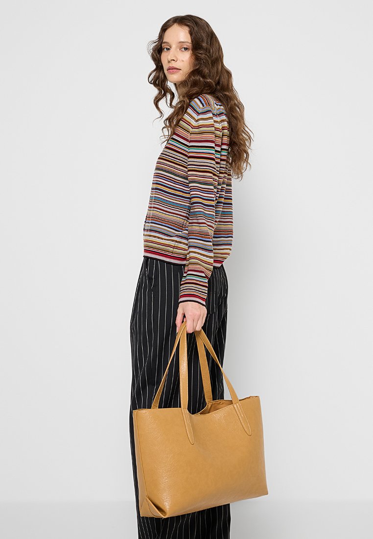 Sac fourre-tout en cuir tan avec deux poignées allongées, forme rectangulaire, texture lisse et design minimaliste.