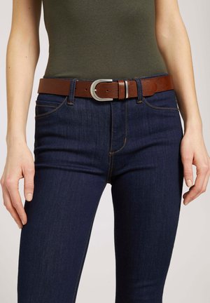 Brauner Ledergürtel mit einer silbernen Schnalle, getragen über dunkelblauen Jeans. Der Gürtel hat eine strukturierte Oberfläche und ein klassisches Design.