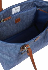 Borsa tote in denim con dettagli in pelle marrone, chiusura con zip e un ampio interno con rivestimento blu e tasche organizzative.