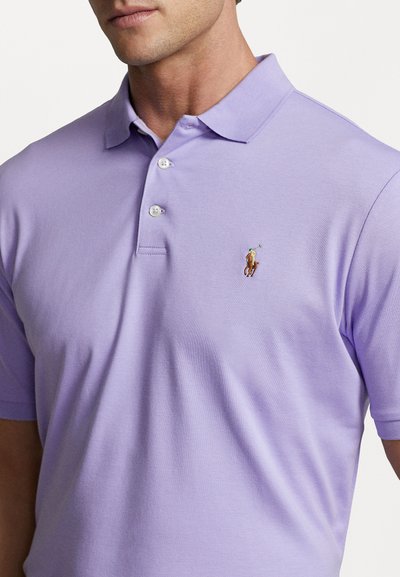 Hele lilla puuvillane polo särk, millel on kolme nupuga kaelus ja lühikesed varrukad. Rinnal on väike broderi logo.