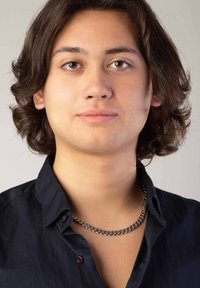 Zwarte overhemd met kraag, voorzien van een zilveren kettinghalsband. Onderwerp heeft halflang, golvend haar en een neutrale huidskleur.