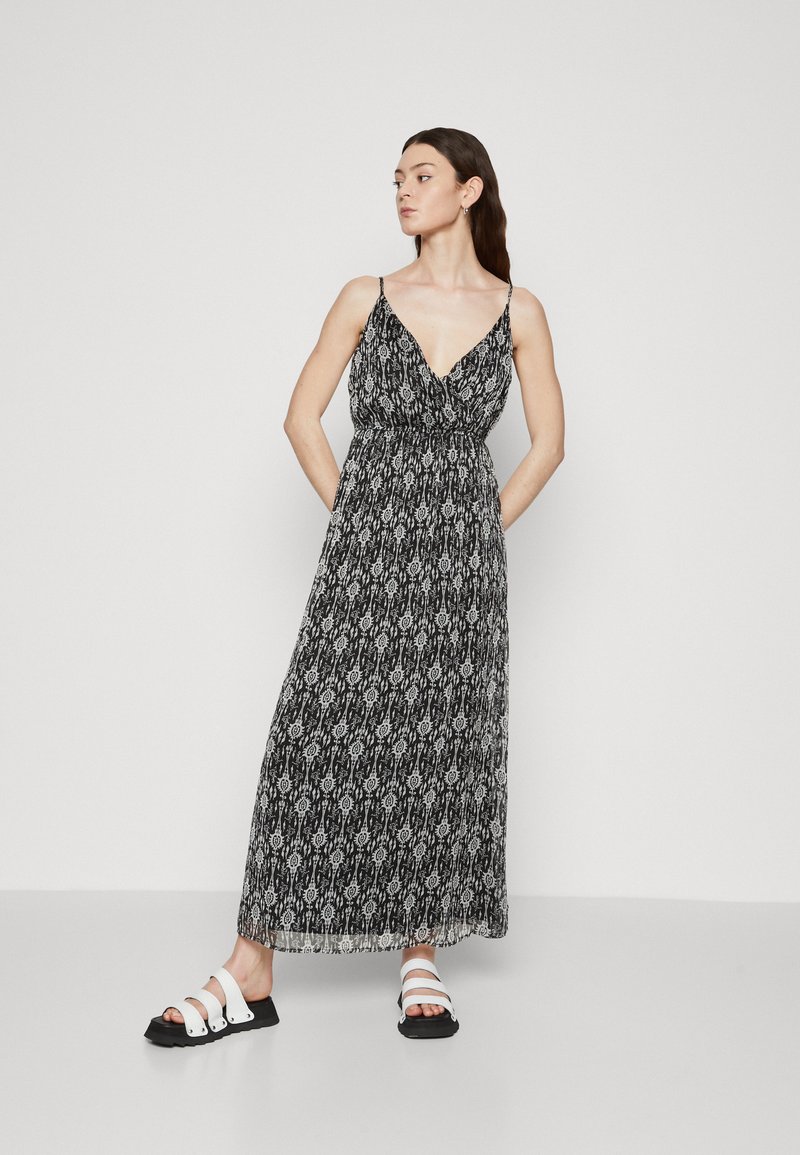 Rochie maxi cu un model alb-negru, decolteu în V, bretele subțiri ajustabile și o siluetă fluidă. Purtați cu sandale alb-negru.