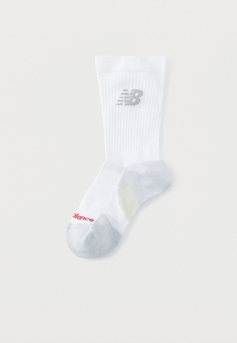 Chaussette blanche à tige courte avec talon et pointe gris, arborant un logo "NB" gris sur le mollet et un texte "New Balance" rouge près de la pointe.