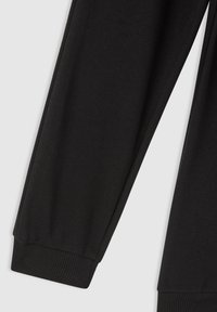 Czarne nogawki z tkaniny z ribbaminowymi mankietami, gładka faktura, prezentowane na jasnym tle.