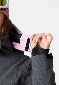 Graue Skijacke mit strukturierter Oberfläche, schwarzem und pinkem Innenfutter, verstellbaren Bündchen und einem Klettverschlussdetail am Ärmel.