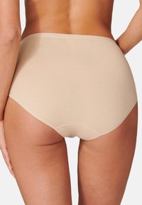 Culottes beiges en coton taille haute, avec des bords sans coutures, une texture lisse et un design minimaliste, présentant des coutures renforcées au niveau des ouvertures des jambes.
