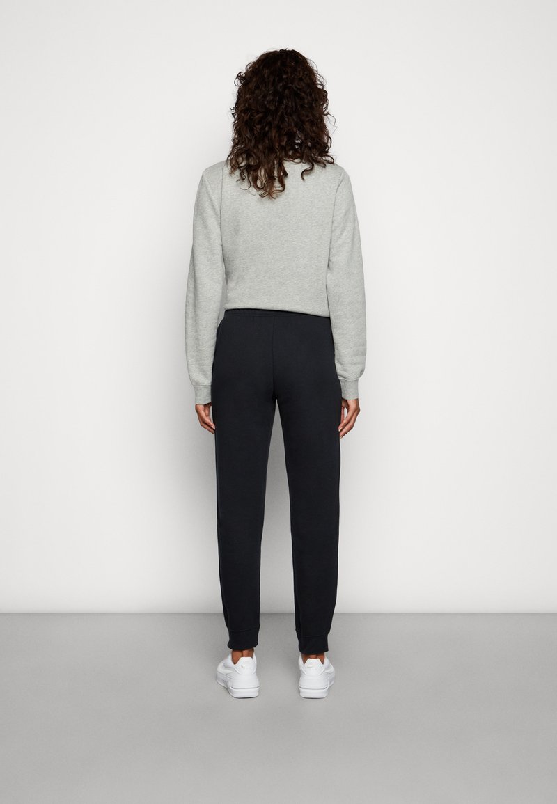 Sweatshirt gris court avec des manches longues associé à un jogging noir fuselé, doté d'une taille élastique et de chaussures de sport blanches.