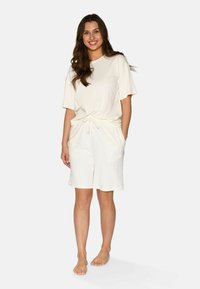 Light beige short-sleeve top and matching shorts made of ribbed fabric, featuring an elastic waist, drawstring, and side pockets.