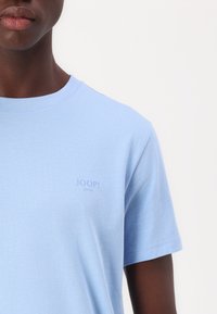 Világoskék pamut póló kerek nyakkivágással. A bal mellen található egy kicsi, diszkrét "JOOP! JEANS" logó. Puha tapintású, rövid ujjú.
