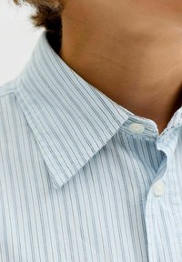 Světle modrá košile s límečkem a tenkými bílými a tmavě modrými pruhy, se zapínáním na knoflíky a texturovanou tkaninou. Detailní pohled na límec.
