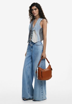 Gilet di denim con pannello a strisce, abbinato a jeans azzurri a gamba larga. Borsa marrone con manico intrecciato e dettaglio con zip.