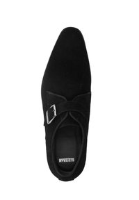 Black suede shoe with a pointed toe, featuring a single adjustable strap and metallic buckle, smooth texture, and minimalistic design.