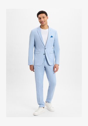 Lichtblauw pak met een op maat gemaakte pasvorm, voorzien van een enkelvoudig gebreid blazer, notched lapels en twee frontzakken. Gecombineerd met een wit T-shirt en witte sneakers.