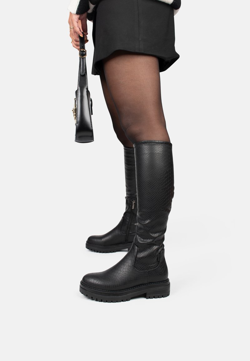Botas negras hasta la rodilla hechas de cuero sintético texturizado, con cremallera lateral, suela gruesa y un sutil patrón de serpiente.