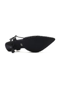Zwart puntig-teen schoen met een gestructureerde bovenkant van kralen, enkelbandje en een gladde platte zool, voorzien van een klein gespsymbool.