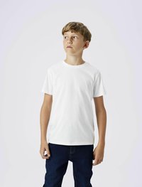 Tricou alb cu mânecă scurtă, realizat din bumbac moale, purtat cu blugi denim de culoare albastru închis, având o croială lejeră și un gât rotund.