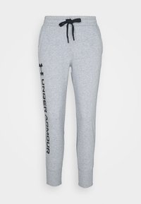 Pantalones de chándal grises con cordón negro, pernera ajustada y el logo "UNDER ARMOUR" impreso verticalmente en la pierna izquierda. Tejido suave y texturizado.