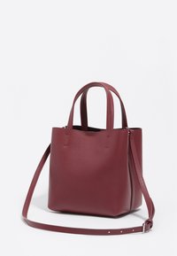 Bordowa torba typu tote z podwójnymi uchwytami i regulowanym długim paskiem na ramię na białym tle.