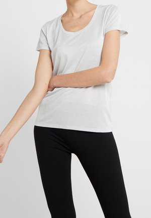 Lichtgrijze T-shirt met korte mouwen en een ronde halslijn, gemaakt van een licht glanzende stof; gecombineerd met zwarte leggings.
