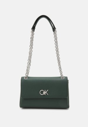Sac à main en cuir vert avec une bandoulière chaîne argentée et une poignée supérieure noire. Présente un emblème logo argenté à l'avant. Design minimaliste.