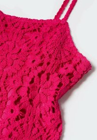 Haut crochet rose avec motifs floraux, fines bretelles ajustables et un design en dentelle texturée. Tissu léger et détails en maille ouverte.