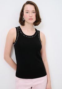 Zwart mouwloos topje met ronde halslijn, voorzien van prominente strass details langs de schouders en halslijn. Zachte, gladde textuur.