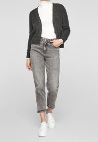 Grijze cardigan met ribbeltextuur, drie knopen, gecombineerd met hooggeschnitte, vervaagde grijze jeans en witte sneakers. Eenvoudige en casual outfit.