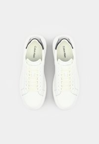 White sneakers with a smooth leather upper, round toe, lace-up design, and subtle branding; features a textured sole for grip.
