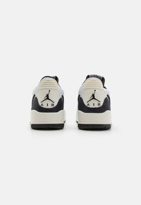 Fehér és fekete sportcipők, texturált sarokkal, "AIR" logóval és Jumpman emblémával a hátsó részen. Gumi talp a tapadás érdekében.